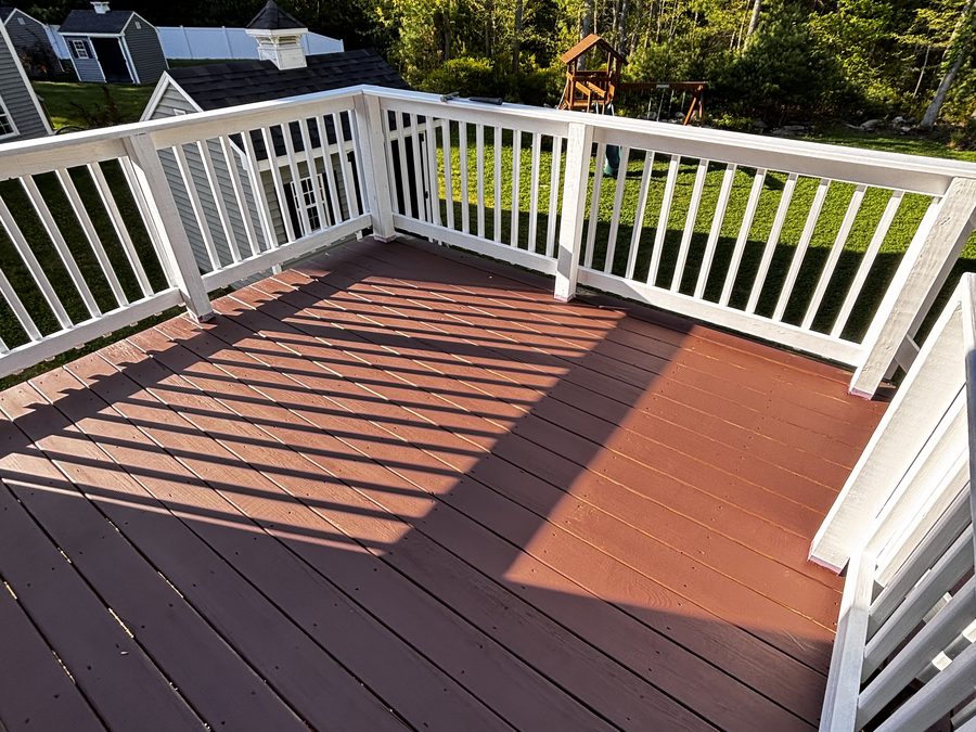 After: backyard deck refinished dark red with white railing — Crafted Edge Construction